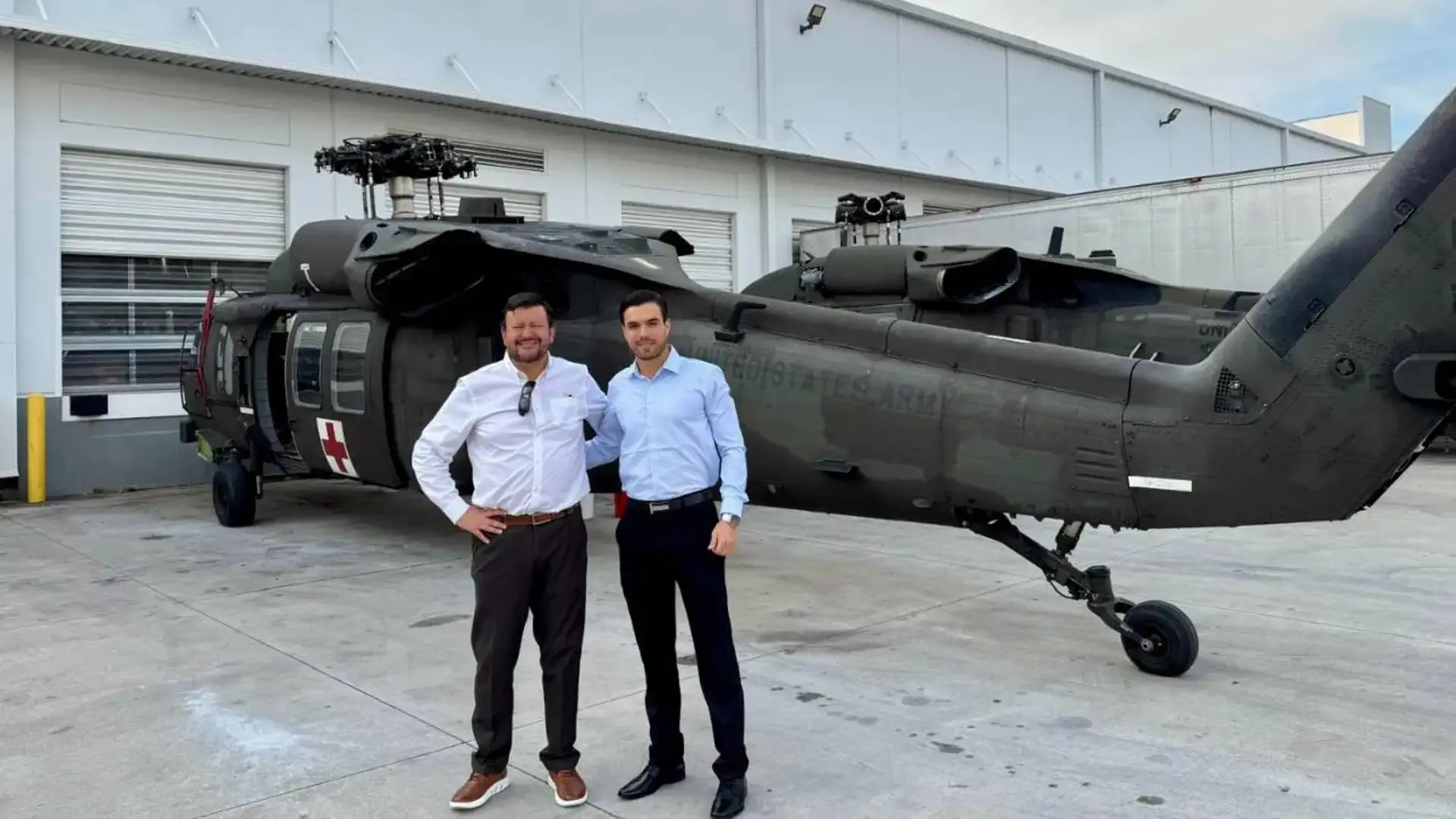 Two men are positioned next to a sleek black helicopter, highlighting their connection to aviation and adventure.