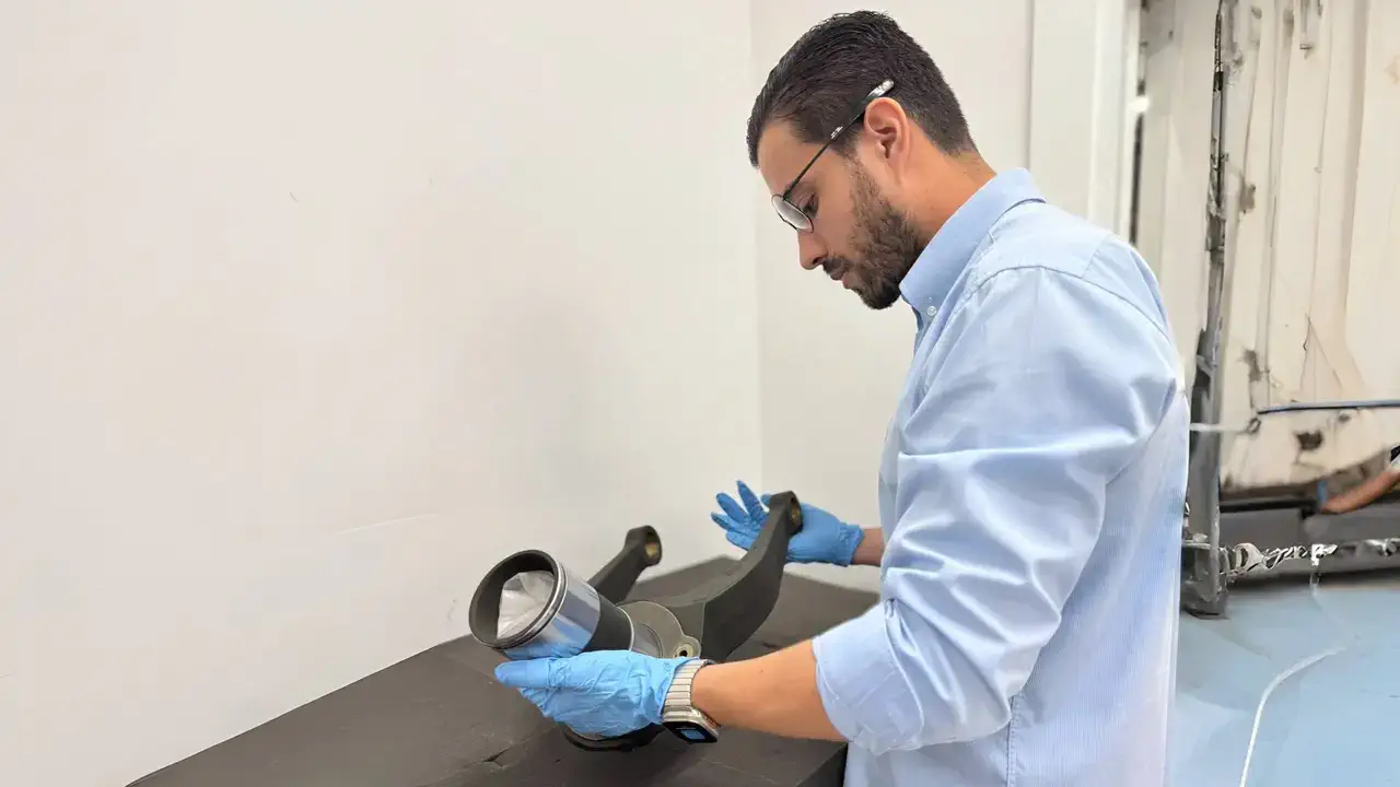 A man wearing gloves an inspecting an aviation part.