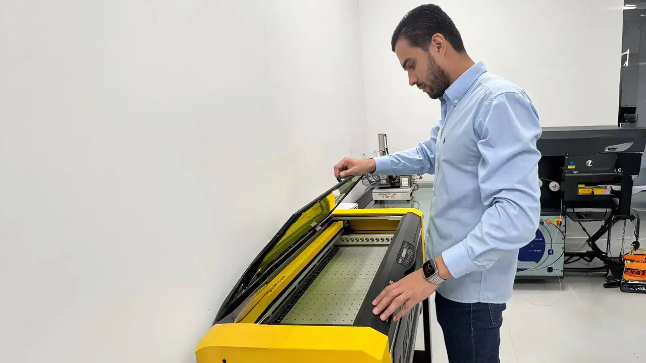 A man standing in front of a specialized equipment, opening its upper compartment.